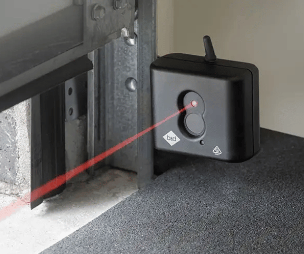 Technician aligning garage door safety sensors on residential door in San Francisco Bay Area