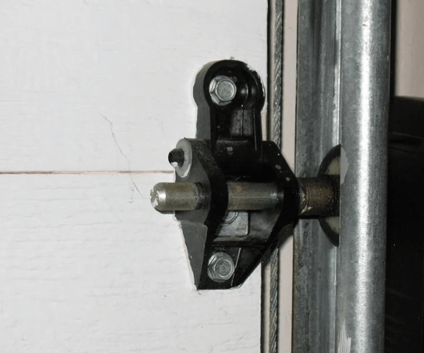 Technician replacing damaged garage door hinge on residential door in San Francisco Bay Area